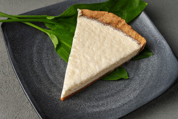 Vegetarian cheesecake on a gray plate with green leaves