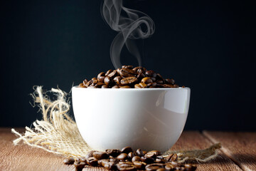 Coffee beans in a white cup on a wooden surface. Copyspace and international coffee day