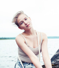 young blond woman hanging on birch tree at lake shore, summer vacations outdoor lifestyle