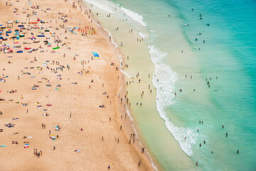 View of ocean beach drone view. Beautiful long ocean beach with umbrellas and people. Nazare, Portugal.