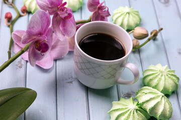 A Cup of coffee, marshmallows, and an Orchid on a light wooden table. top view.