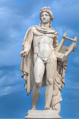 Fototapeta na wymiar Apollo statue with golden decorations against blue sky