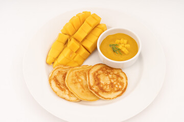 Breakfast pancakes on a plate with mango and sweet mango sauce.