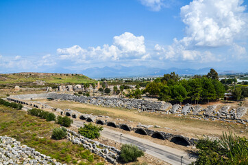 The stone ruins with the parts of sits and staircases of ancient antic stadium in Perge, Antalya, Turkey.