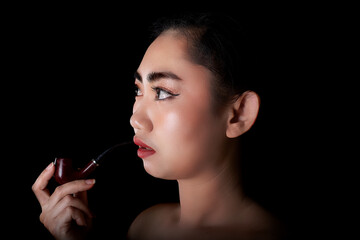 Obraz premium Portrait beautiful Asia young women with a smoking pipe tobacco on the black background