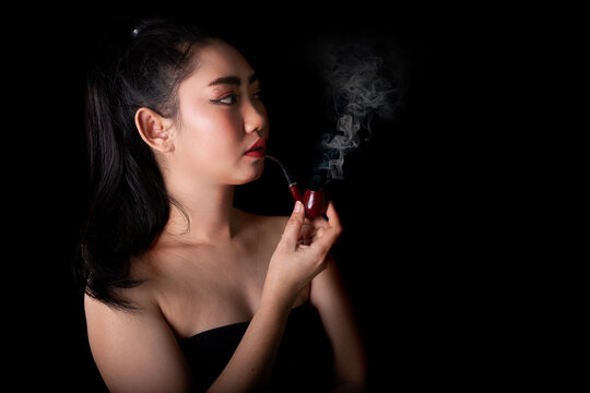 Portrait beautiful Asia young women with a smoking pipe tobacco on the black background