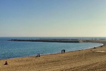 Panoramic view of sand beach inlet and pier with few people