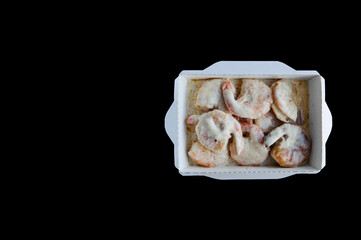 food with home delivery, shrimp in cream sauce in a disposable box on a black background