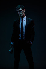 Fototapeta premium Futuristic neon lighting. A man in blue and red contrasting lighting, wearing a jacket in a white shirt and tie with a facial injury, bandaged hand