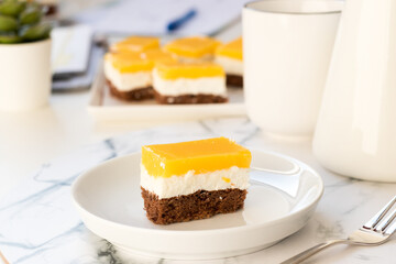 Layered cake with cocoa sponge cake, mascarpone cream and orange jelly on top