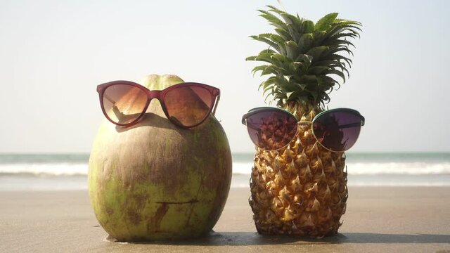 Tourists pineapple and coconut in sunglasses on the beach