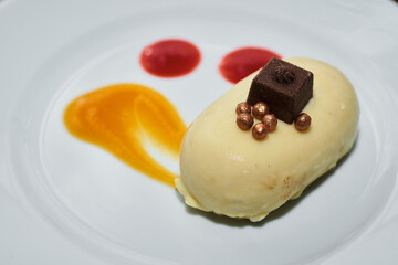 Romantic pastry dessert. Small individual portion of trendy mousse filled mini no bake cake coated with smooth white chocolate. Nicely decorated with orange sauce and coffee grains on top.