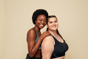 Workout. Diversity Women Portrait. Multi-Ethnic Slim And Plus Size Models Against Beige Background. African And Caucasian Women In Black Sportswear Holding Pilates Ball And Mat. Fitness As Lifestyle.