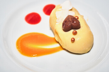 Romantic pastry dessert. Small individual portion of trendy mousse filled mini no bake cake coated with smooth white chocolate. Nicely decorated with orange sauce and coffee grains on top.