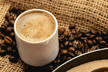 White coffee cup with roasted beans on sackcloth