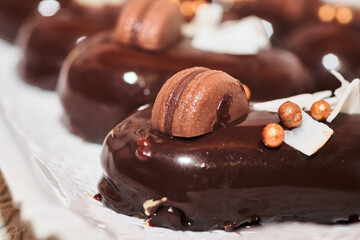 Detailed close up image of a fancy french dessert. Gourmet mini cakes dark chocolate shiny glaze and nice sweets decoration.