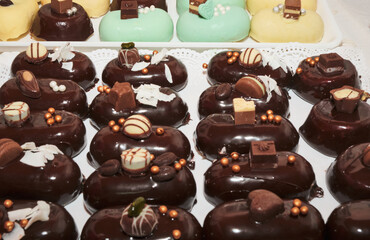 Not baked individual portions of mini mirror chocolate glazed cakes. Stuffed with delicious flavored mousse ice cream. Yummy sweet appetizers and nicely decorated. Michelin star level gourmet.