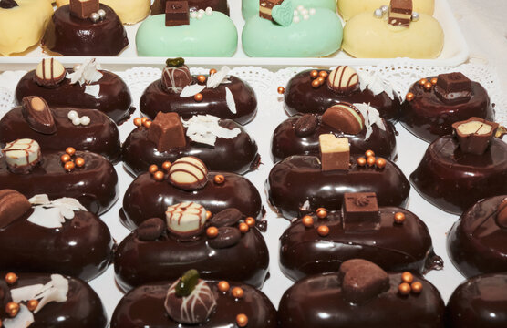 Not baked individual portions of mini mirror chocolate glazed cakes. Stuffed with delicious flavored mousse ice cream. Yummy sweet appetizers and nicely decorated. Michelin star level gourmet.