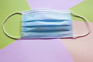 Medical protective mask on colored paper background. Space for text