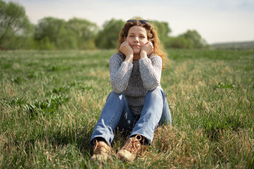 A woman sits on the grass in a meadow