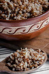 buckwheat porridge in a clay plate with butter and a wooden spoon