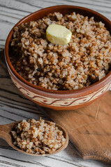 buckwheat porridge in a clay plate with butter and a wooden spoon