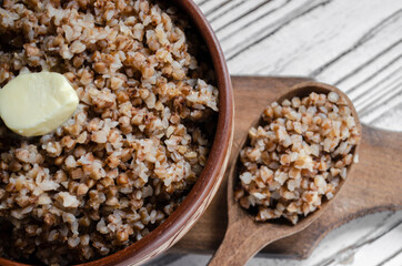 buckwheat porridge in a clay plate with butter and a wooden spoon