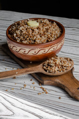 buckwheat porridge in a clay plate with butter and a wooden spoon
