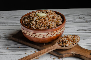 buckwheat porridge in a clay plate with butter and a wooden spoon