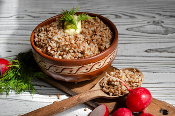 buckwheat porridge in a clay plate with butter and a wooden spoon