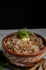 buckwheat porridge in a clay plate with butter and a wooden spoon
