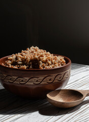 buckwheat porridge in a clay plate with butter and a wooden spoon