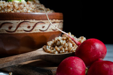 buckwheat porridge in a clay plate with butter and a wooden spoon