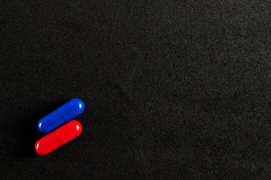 Dois comprimidos coloridos em azul e vermelho em fundo preto.