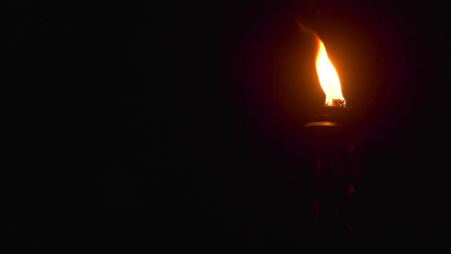 Flame of a tiki torch burning at night