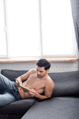 handsome sexy shirtless man reading book on sofa