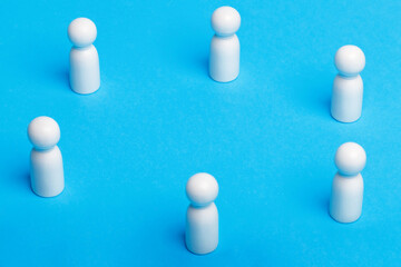 Social distancing conceptual image. White wooden figures of people keep distance on blue background