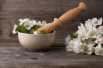 Flowers of apple tree and mortar on vintage wooden background, concept of natural cosmetics, aromatherapy, phytotherapy. Useful properties of medicinal herbs