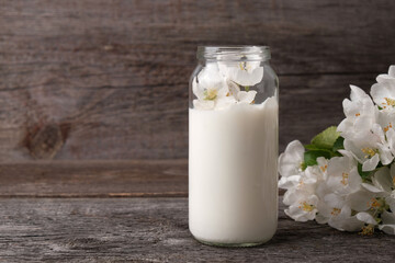 Milk from apple tree flowers on vintage wooden background with copy space, concept of natural cosmetics, aromatherapy, herbal medicine