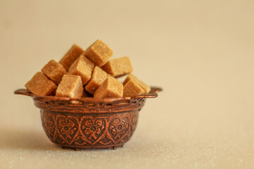 Decorative sugar bowl filled with brown sugar cubes, selective focus, free copy space