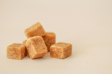 Close up on brown sugar cubes, selective focus, free copy space, light background