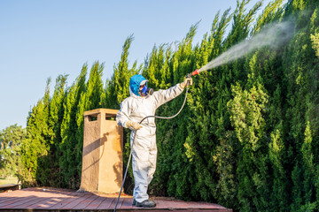Fumigator applying plant protection products and herbicides to the plants of a house with a garden...