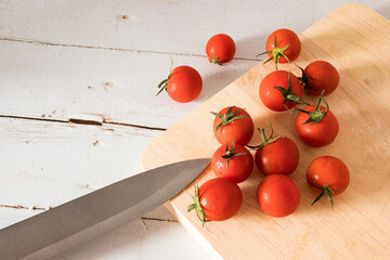Red tomato on a cutting board wiht wooden background.