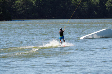 a man rides a surfboard on a river on a rope on a rope against the background of the forest . learning to surf