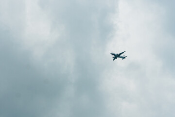 Naklejka na ściany i meble Plane flying in a cloudy sky and preparing to land on a tropical island.