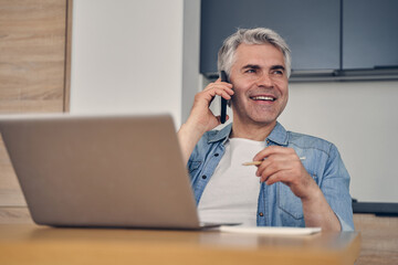 Grey-haired male sitting in the kitchen indoors