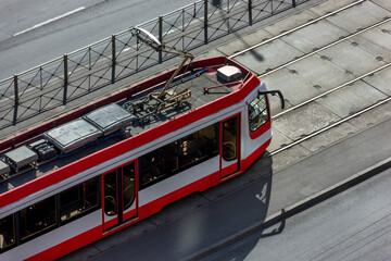 The urban red modern tram moves along the train track. Ecological, social transport of citizens