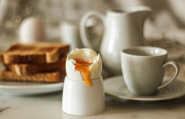 Breakfast concept: close up on boiled egg, rest of the table setting in the background, selective focus