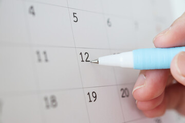 Hand with pen writing on calendar date