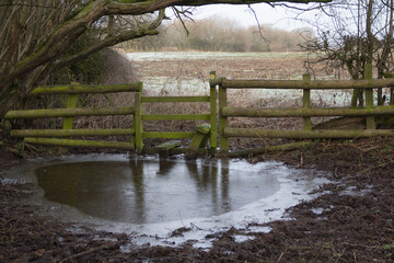 Stile leading into a frozen pool of water on a cold winters day in rural Shropshire UK